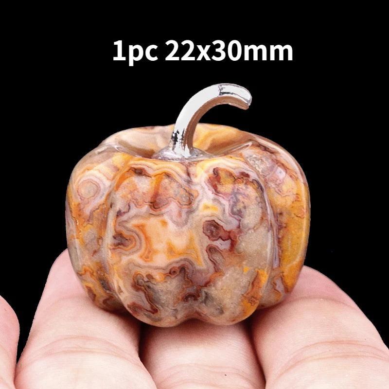 A natural stone pumpkin figurine with a silver stem, shown in a person's hand.