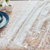 A white vintage lace tablecloth draped over a wooden table with blue plates and floral accents.