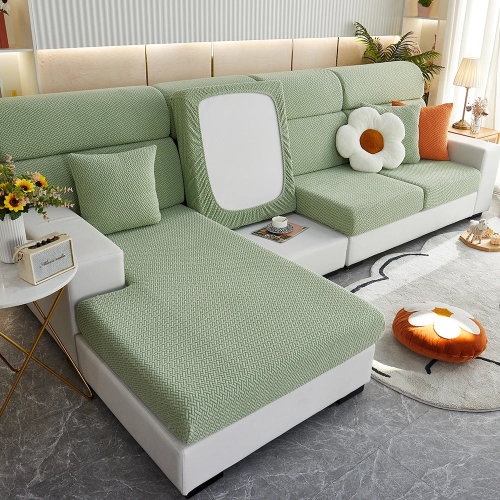 A light green Jacquard sofa slipcover with white cushions and elastic edges in a modern living room setting.