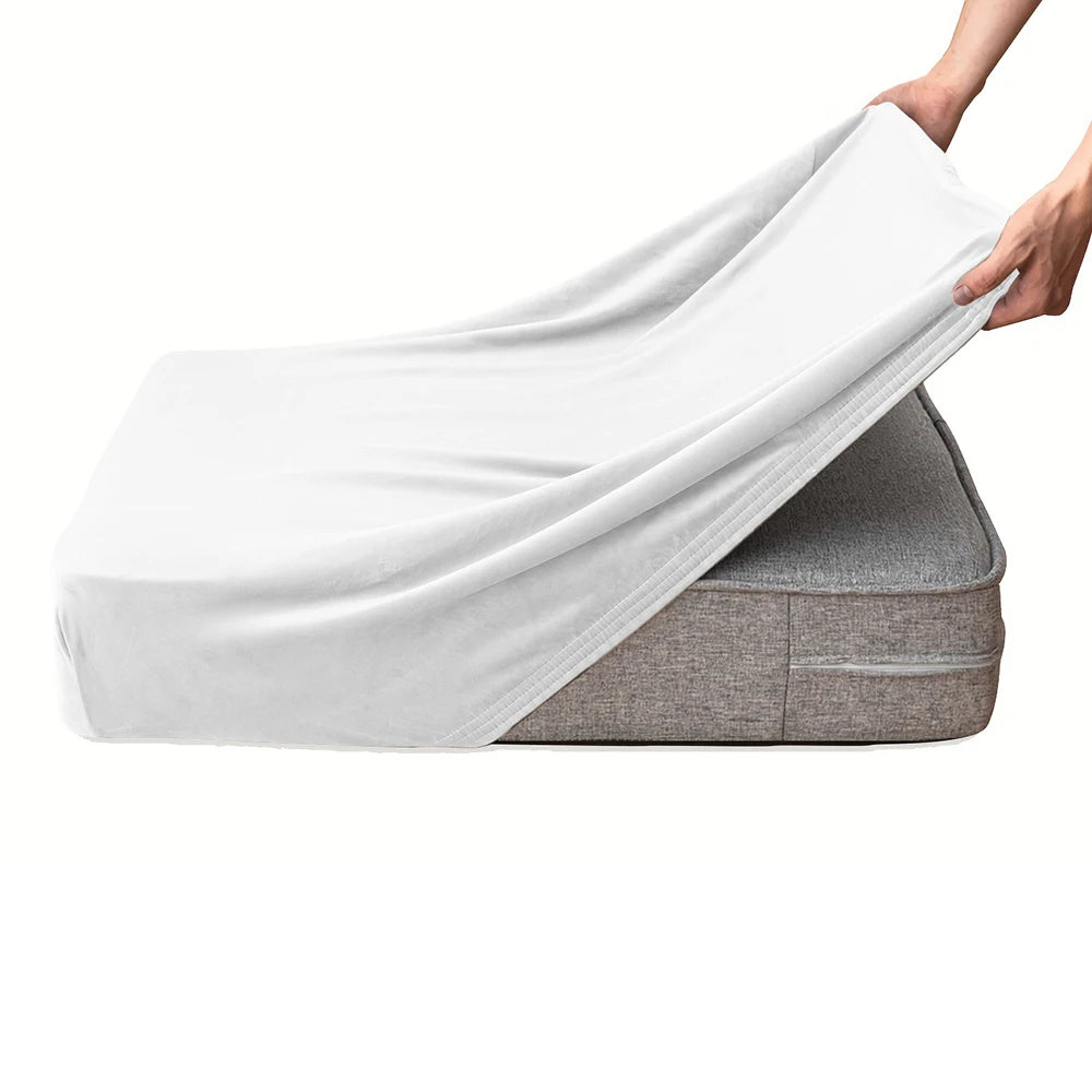 A hand is draping a white velvet stretchy sofa seat cover over a gray cushion.