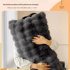 A person is holding a thick, gray faux fur pillow cover, demonstrating its warmth for winter sleep.