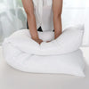 A white extra-long body pillow is shown being held by a person, demonstrating its full-body support.