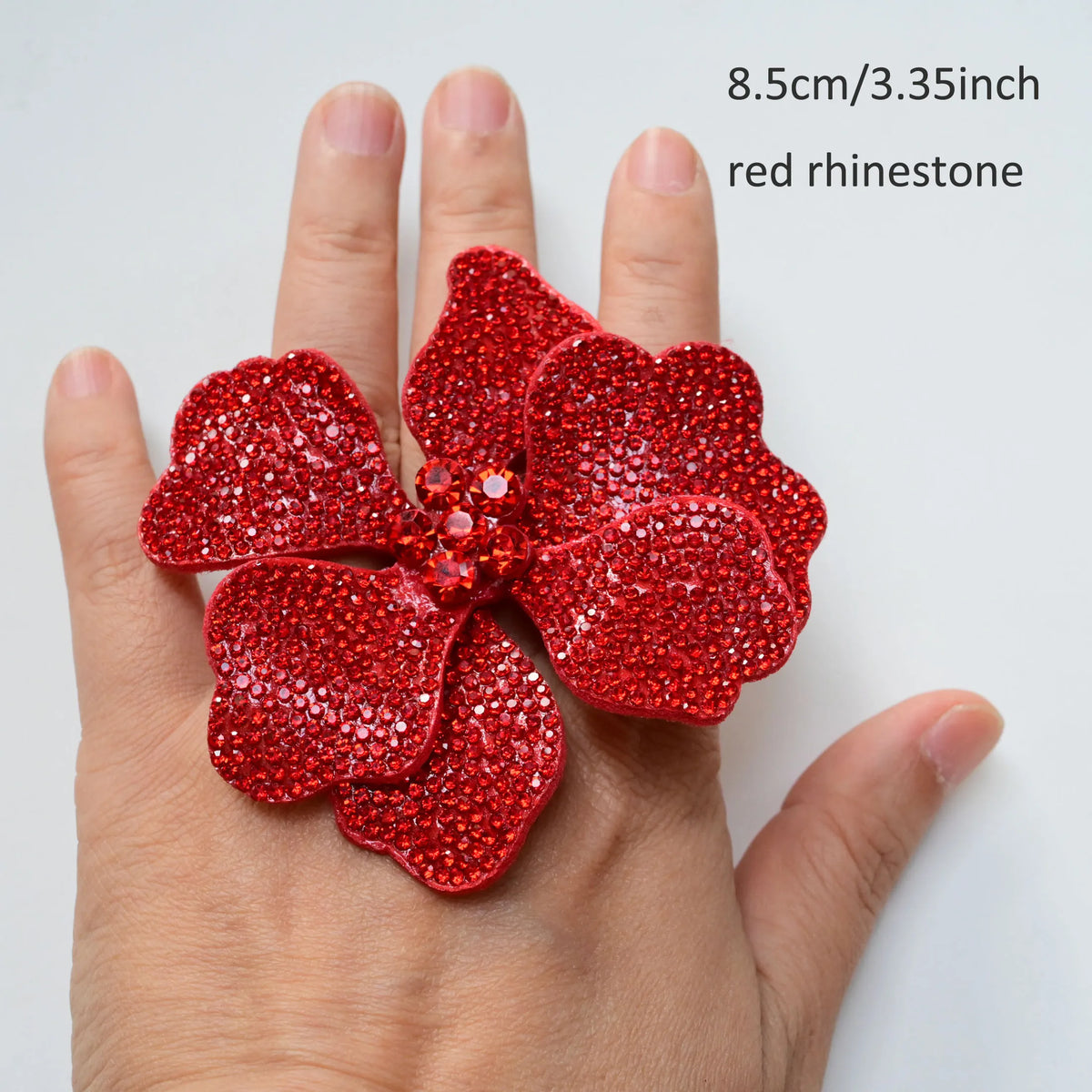 A hand holds a red rhinestone flower applique patch, measuring 8.5cm/3.35inch.