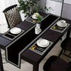 A set of luxury geometric placemats and table runners featuring black and white patterns on a dark wooden table.