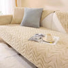 A beige plush sofa seat cushion cover with a quilted texture and a gray accent pillow on a light-colored sofa.