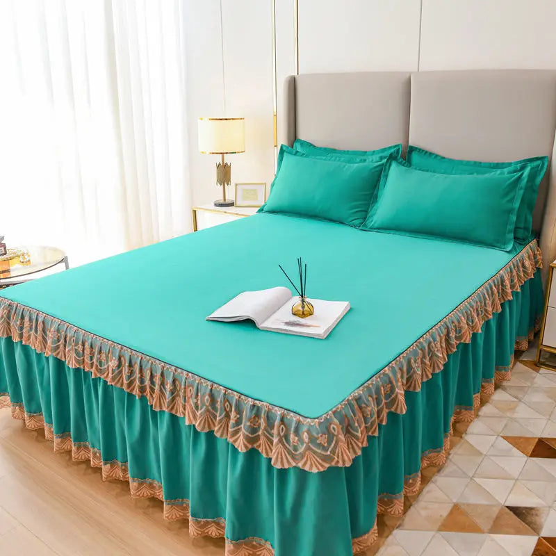 A teal luxury floral bed skirt covering a mattress, displayed in a bright bedroom setting.