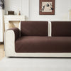 A modern sofa with dark brown quilted cushion covers and light cream upholstery in a bright room.