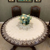 Elegant lace-trimmed round tablecloth set on a dark wood table with wooden chairs in the background.