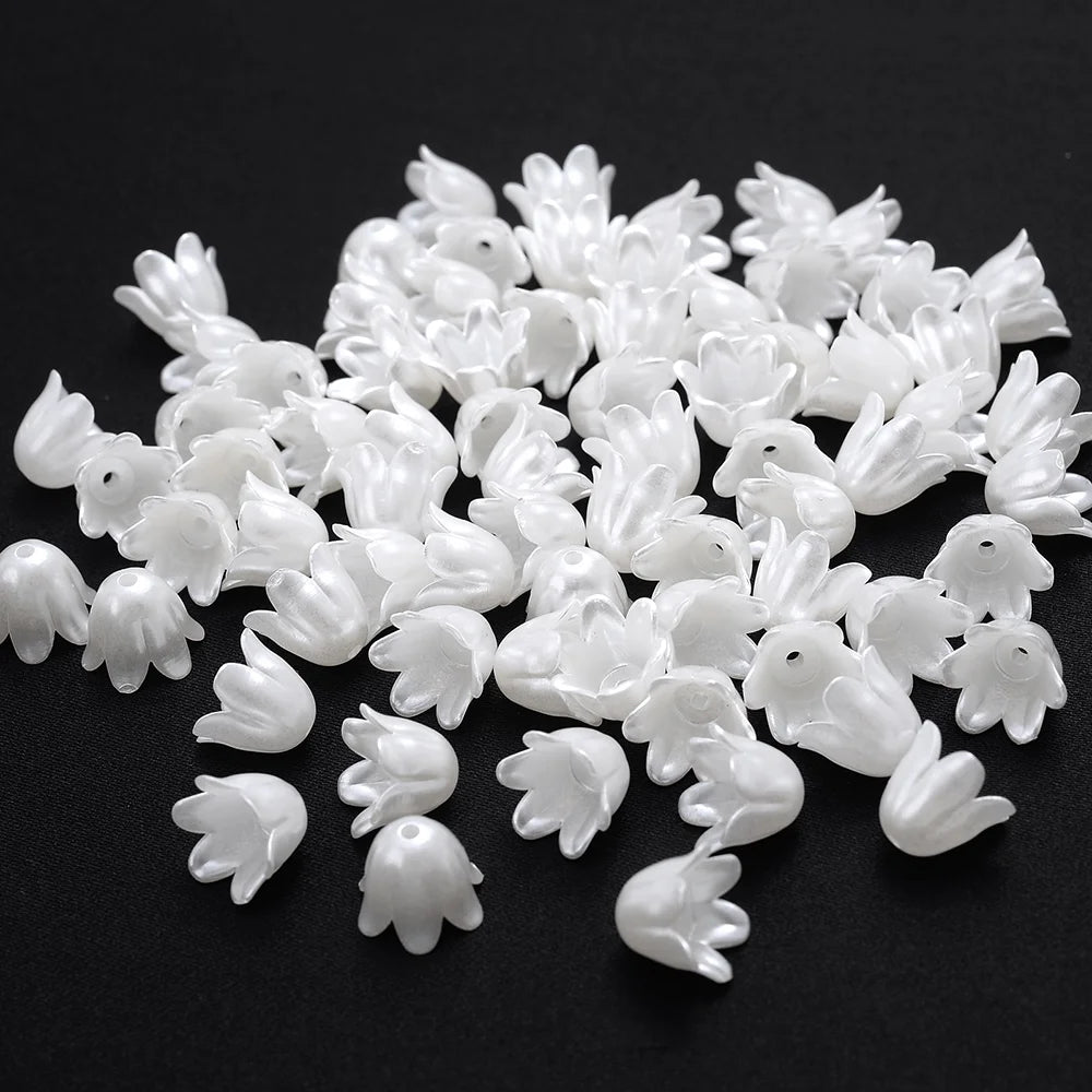 A pile of small, white imitation pearl flower spacer beads for DIY jewelry.