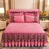 Pink quilted bed skirt with lace trim and embroidery on a pink quilted bed.