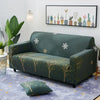 A dark green stretch sofa with a patterned slipcover and a modern floral art print on the wall.