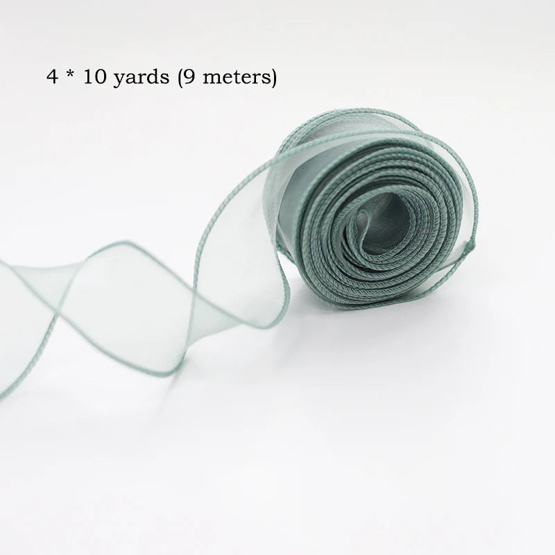 A roll of sheer, silvery-green silky organza ribbon measuring 4 x 10 yards.