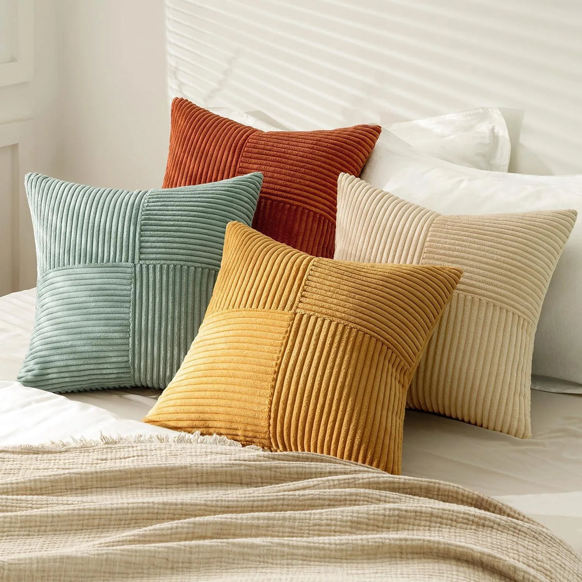 A set of four neutral corduroy throw pillow covers in shades of orange, green, and beige with a patchwork design.