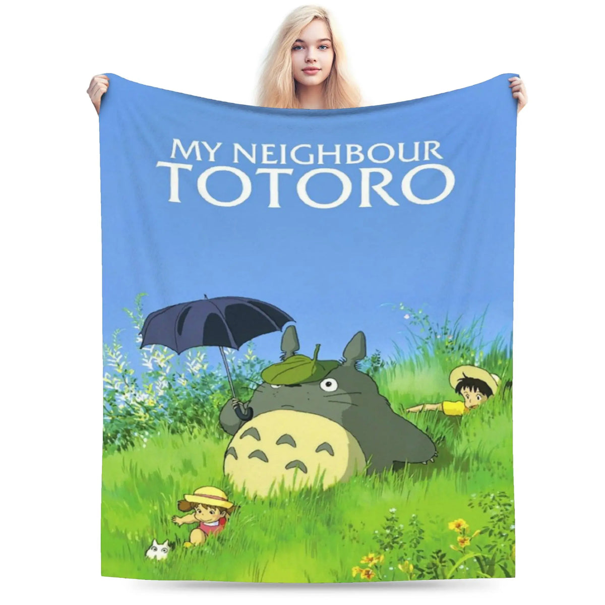 A fabric blanket featuring the Totoro character in a grassy outdoor setting.