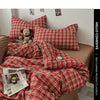 A red and green plaid duvet cover set is displayed on a bed, with pillows and a folded blanket visible.