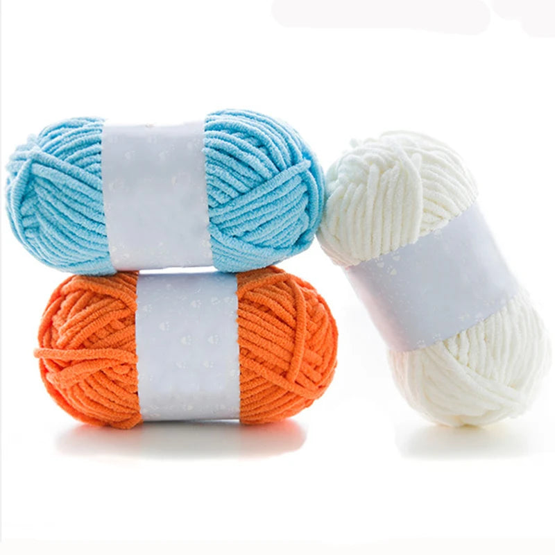Two balls of thick velvet yarn, one light blue and one orange, wrapped with white ribbon.