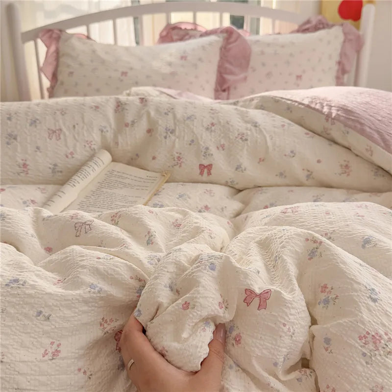 A close-up of a pink and white princess style ruffle bedding set with floral patterns on a bed.