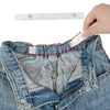 A hand is adjusting an invisible self-adjusting belt tightener on the waistband of blue denim jeans.