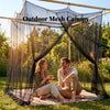 A couple relaxing under an outdoor mesh canopy in a grassy area.