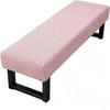 A pink jacquard stretch bench cover with a woven pattern and black frame.