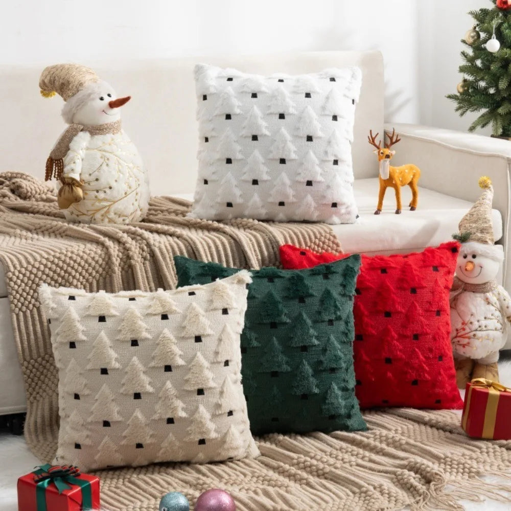 A collection of festive Christmas tree plush throw pillow covers in white, red, and green resting on a beige knitted surface.