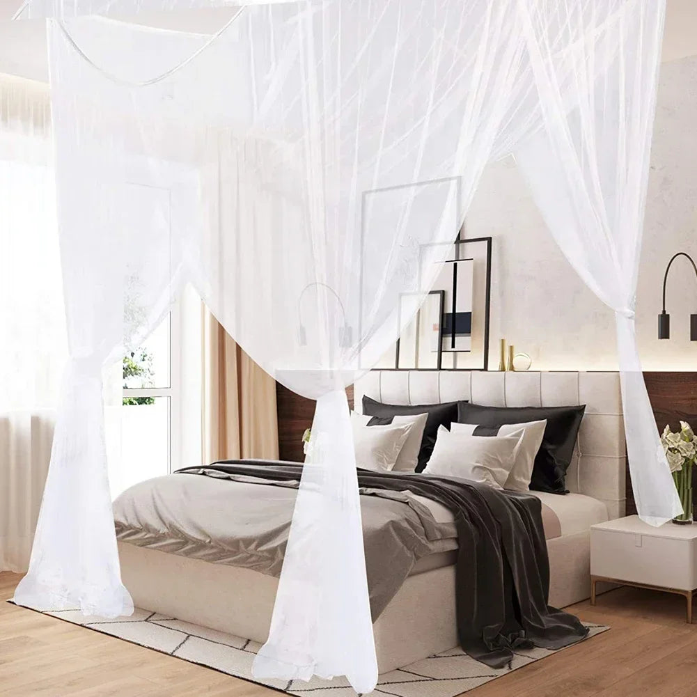 A queen size mosquito net canopy draped over a bed with sheer white fabric and dark bedding.