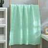 A light mint green 6-layer cotton gauze blanket hanging on a wooden rack.
