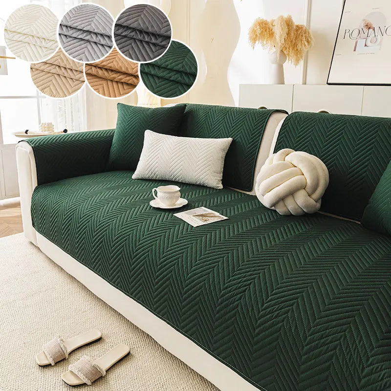 A deep emerald green anti-slip fabric sofa cushion cover with a quilted pattern and decorative pillows.