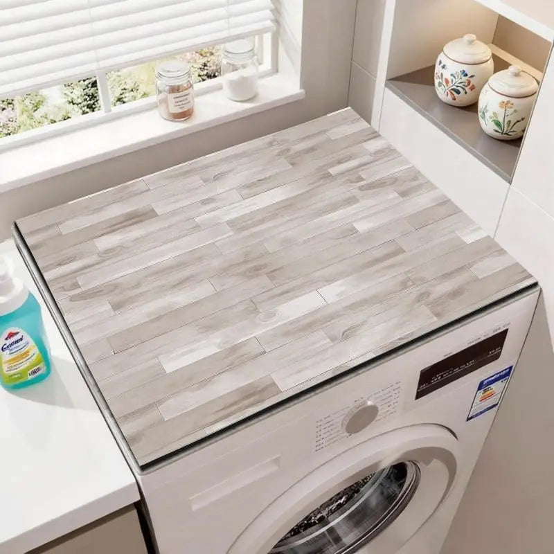 A white washing machine with a wood grain fridge cover mat placed on the top surface.
