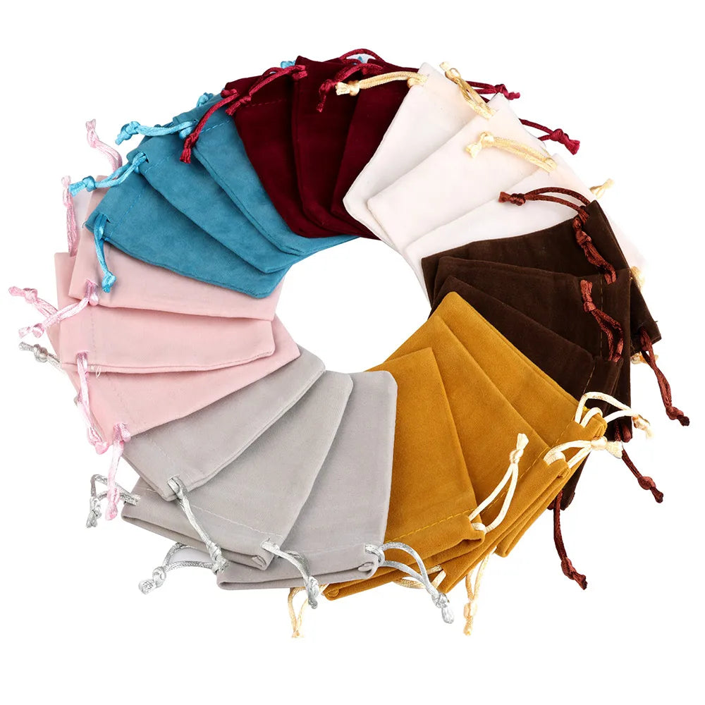 A circular arrangement of velvet drawstring jewelry gift bags in various shades including pink, blue, maroon, brown, and gold