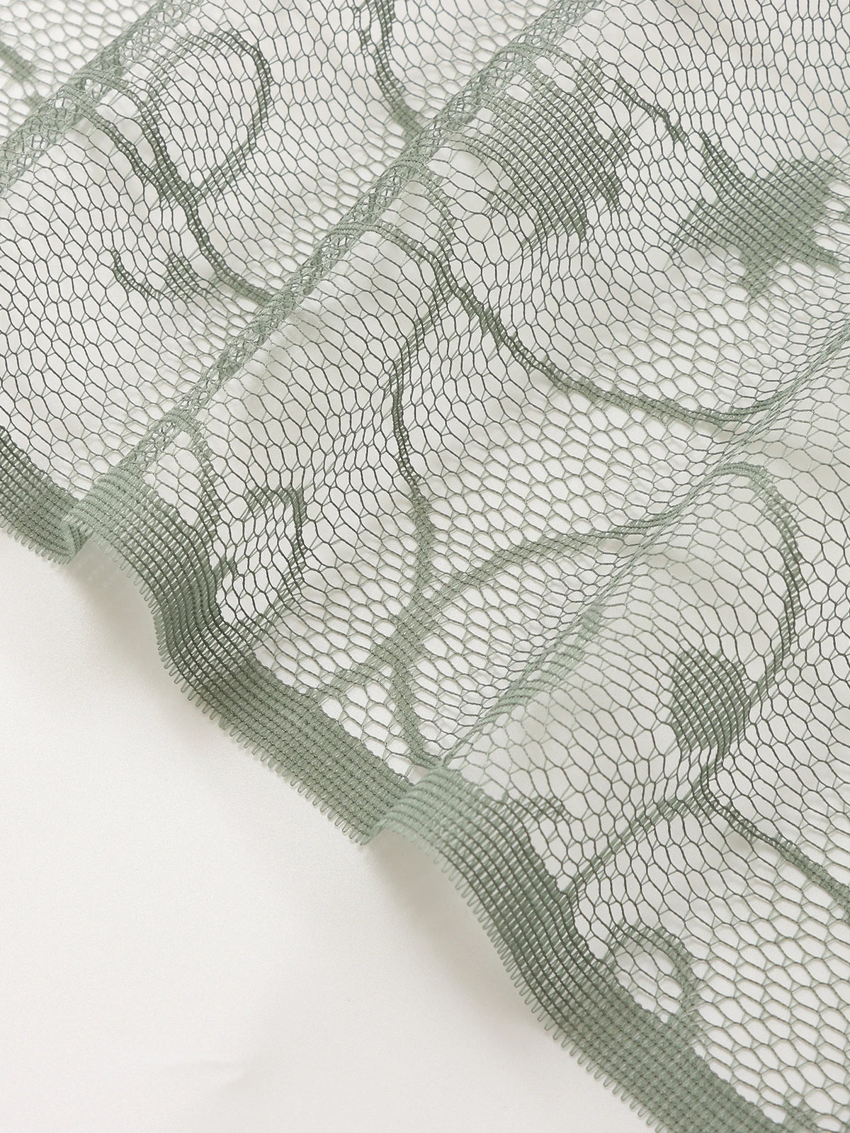 Translucent sun and moon lace door curtain in a muted sage green color