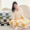 A woman is sitting in front of a window surrounded by stacks of soft flannel panda fleece blankets.