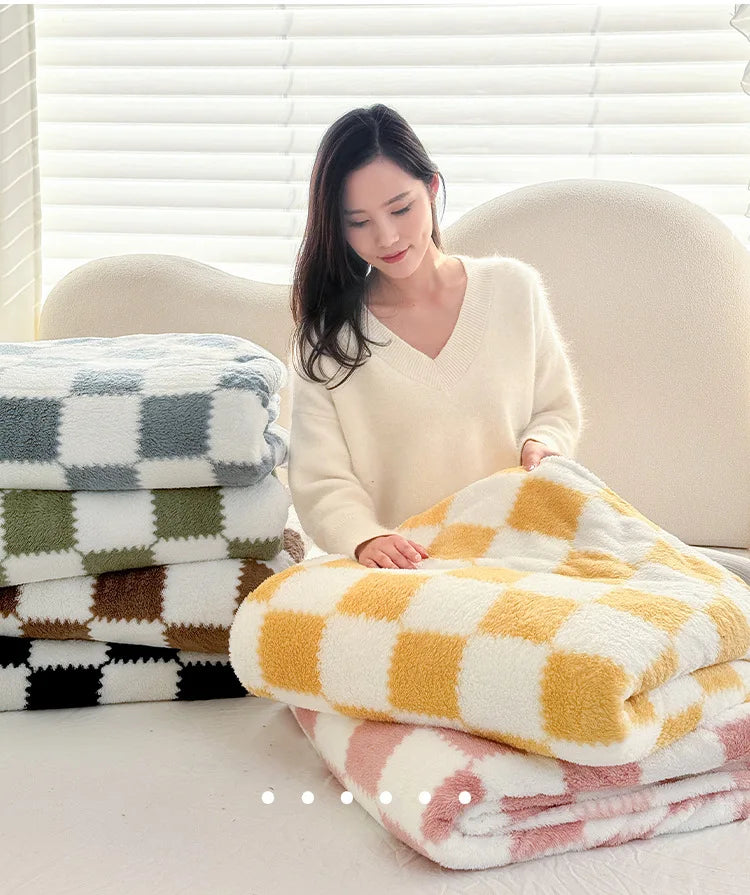 A woman is sitting in front of a window surrounded by stacks of soft flannel panda fleece blankets.
