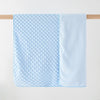 Light blue fleece swaddle blanket with a textured pattern hanging on a wooden rod.