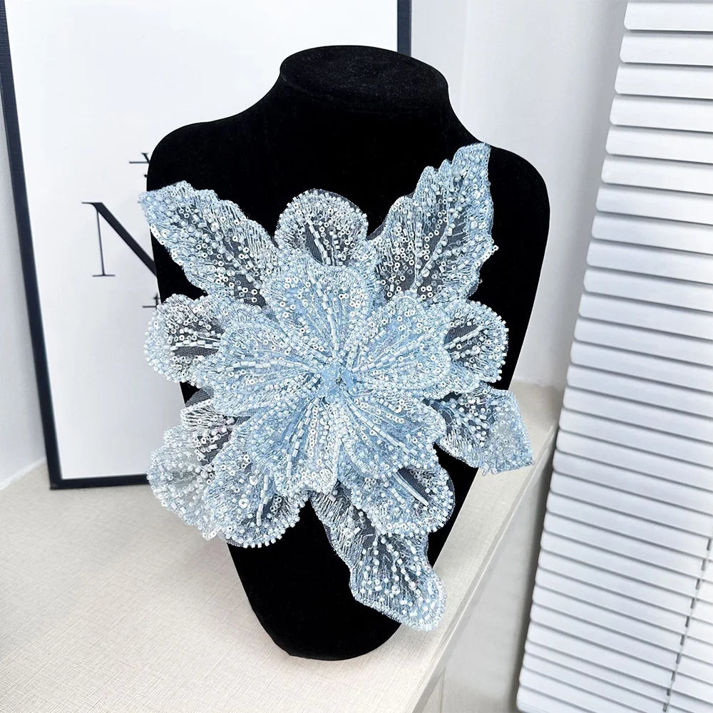 A light blue floral lace applique fabric patch decorated with sparkling sequins displayed on a black mannequin.