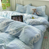 A light blue floral microfiber duvet set with patterned pillows and a teddy bear on a bed.