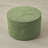 A round, olive green jacquard ottoman footrest slipcover with a textured leaf pattern.