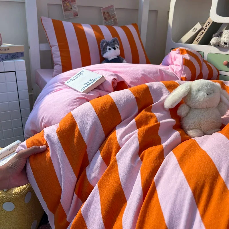 A close-up of an orange and pink striped duvet cover set with a white rabbit plush toy on a bed.