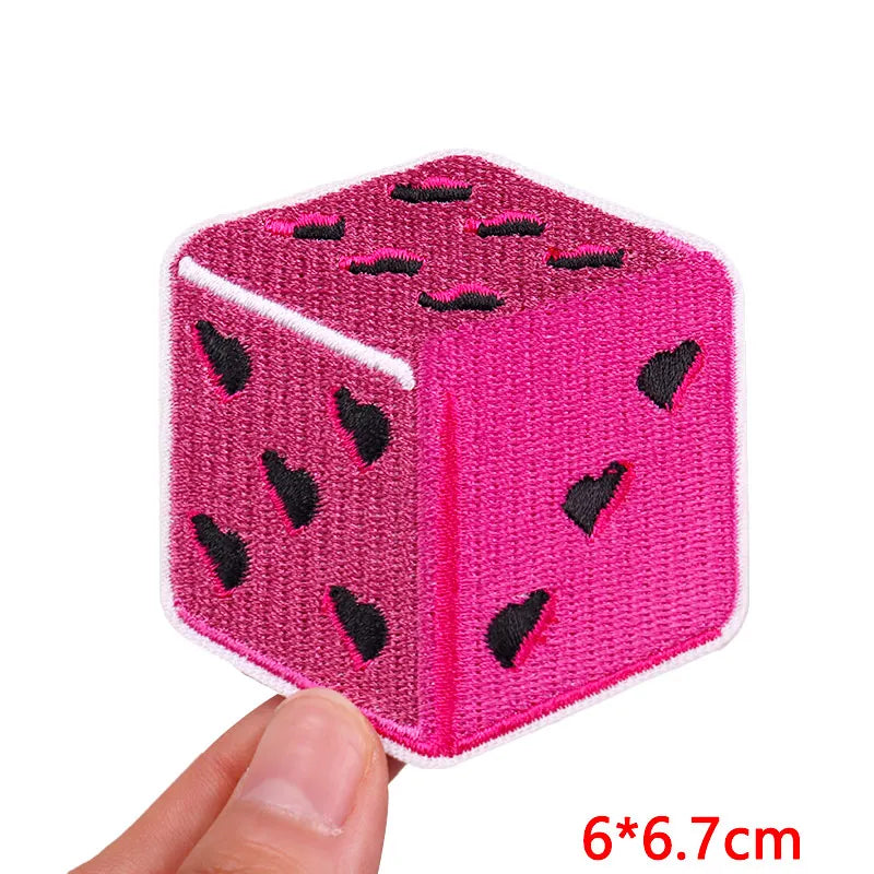A pink felt cube with black embroidered heart shapes on its surface.