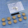 Silver metal button pins are displayed on a white plastic sheet against a blue fabric background.