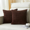 A dark brown corduroy decorative throw pillow cover with a vertical stripe design resting on a white bed.