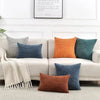 A collection of retro corduroy patchwork pillow covers in various shades of blue, orange, and gray displayed on a sofa.
