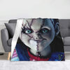 A graphic print of Chucky from the horror movie featured on a gray throw blanket.