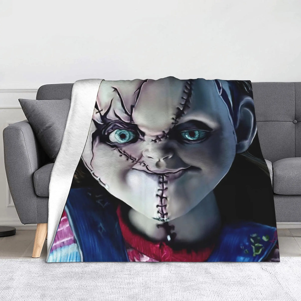 A graphic print of Chucky from the horror movie featured on a gray throw blanket.