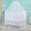 White wooden crib with a sheer white mosquito net canopy draped over it.