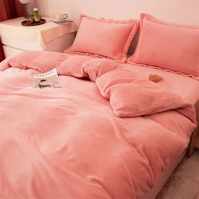A pink luxurious flannel duvet cover set with matching pillows and a blanket on a bed.