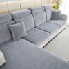 A light gray stretchable chenille sofa cushion cover with matching throw pillows on a modern sofa.