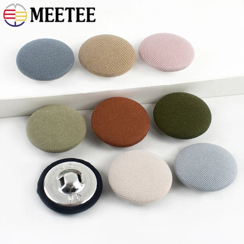 A set of round fabric-covered shank buttons in various shades of gray, beige, and olive green.