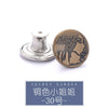 A round, antique brass metal button with the engraved text Jeans Jeans.