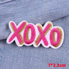Pink and gold embroidered letter patches spelling XOXO on a denim fabric background